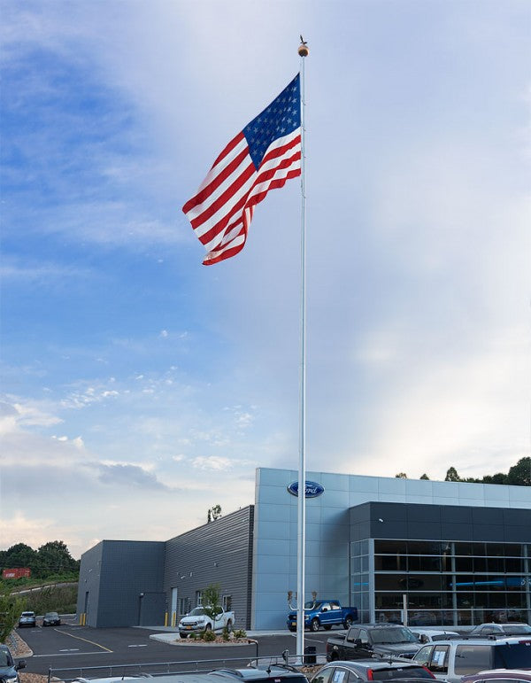 Load image into Gallery viewer, Tall white Apex Series 100 Internal Halyard Aluminum Flagpole flying a large American flag outside a modern commercial building.
