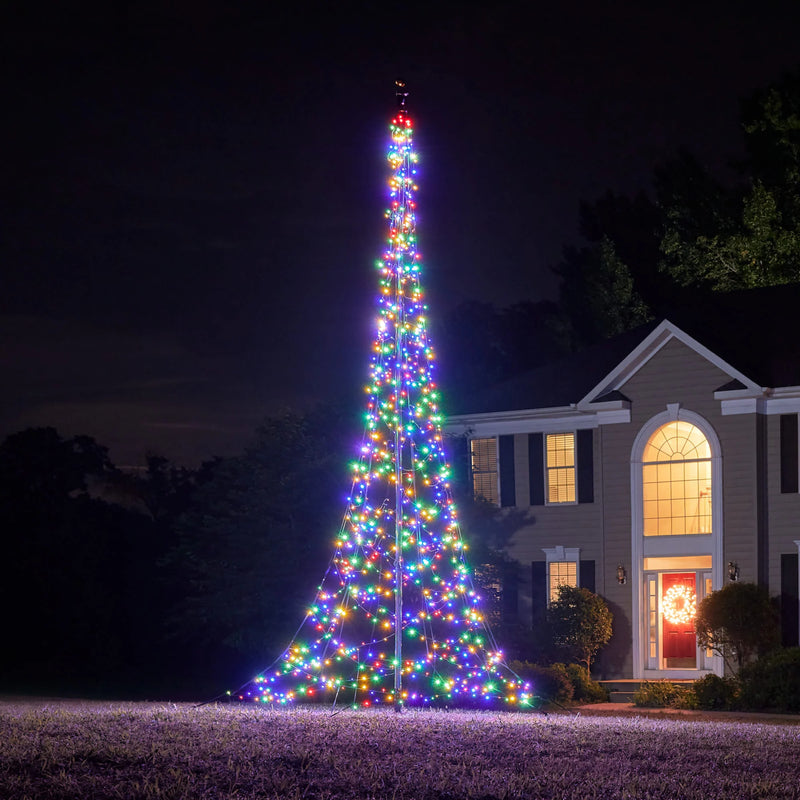 Load image into Gallery viewer, Large, multi-color illuminated Fairybell Flagpole Christmas Tree Light installed in a yard for holiday display at dusk.