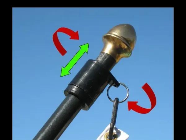 Load image into Gallery viewer, Black Neverfurl anti-furling ring on a dark flagpole with a brass finial, illustrating rotational and vertical movement with arrows.