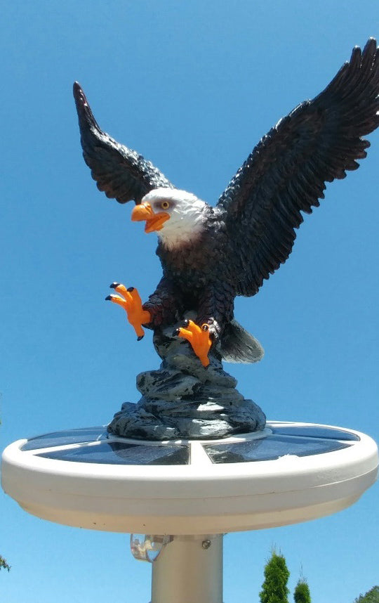 Load image into Gallery viewer, The hand-painted Resin Landing Eagle Flagpole Ornament mounted on top of a round solar light in an outdoor setting.