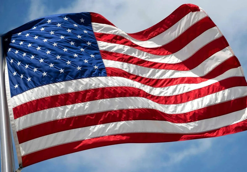 Load image into Gallery viewer, A close-up of a heavy-duty nylon American flag with a focus on its stripes and stars, flying against a blue sky with clouds.