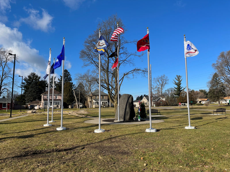 Load image into Gallery viewer, A series of aluminum flagpoles with external halyards, displaying various flags, set against an outdoor backdrop.
