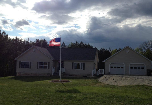 A 45-foot tall aluminum flagpole with an external halyard system, displaying an American flag, installed in front of a house.
