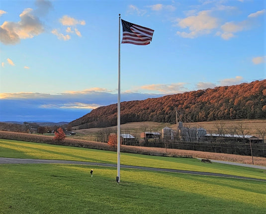 70-foot Lincoln series flagpole installed in field in beautiful farmland, with rolling hills and beautiful sky as a backdrop.