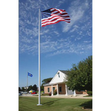 A tall aluminum flagpole with an American flag flying at the top, set against a sky with few clouds, and a building in the background.
