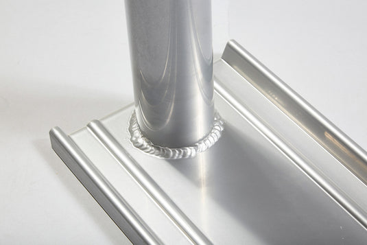 Detailed view of welded joint connecting upright pole sleeve to aluminum flagpole stand base.