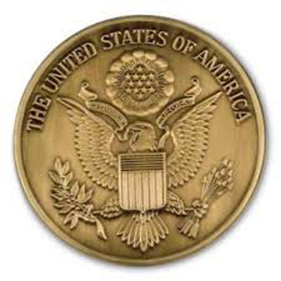 Brass medallion depicting the Great Seal of the United States, centered with the Bald Eagle and a shield on its chest, surrounded by 