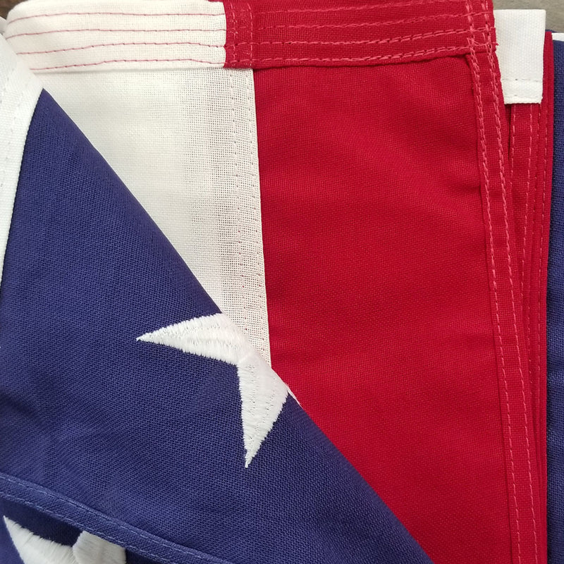 Load image into Gallery viewer, Close-up texture view of the Endura-Tex Cotton Outdoor U.S. Memorial Flag, showcasing the deep red and rich blue colors, durable stitching along the stripes and fly end, and a white embroidered star on the blue canton.

