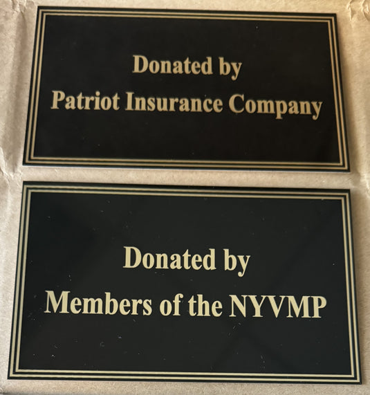 Two examples of black engraved donation plaque plates for flagpoles with gold lettering. The top plate reads 