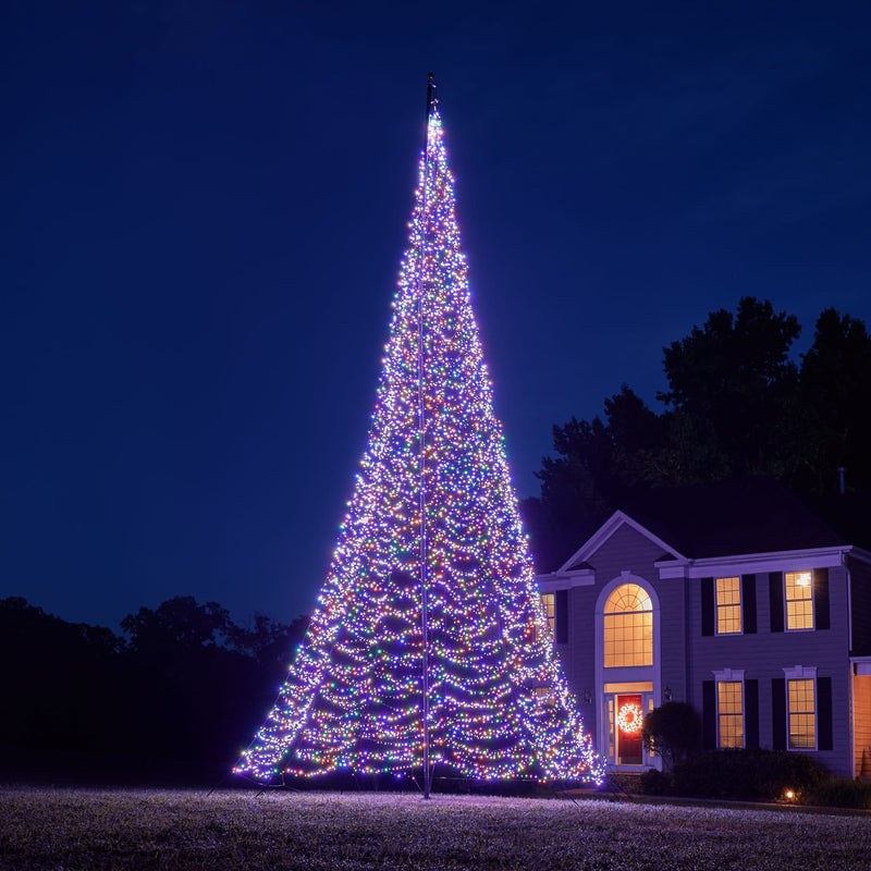 Load image into Gallery viewer, Tall outdoor Fairybell Flagpole Christmas Tree Light displayed in full vibrant multicolor against a dark evening sky.
