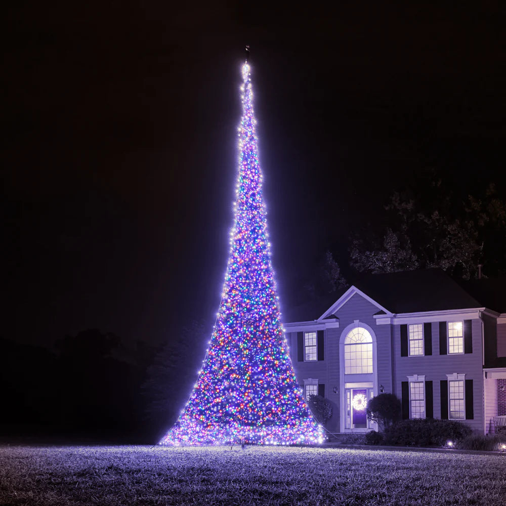 Slightly saturated view of the tall, brightly glowing Fairybell Multi-Color Flagpole Christmas Tree Light illuminating a residential yard.