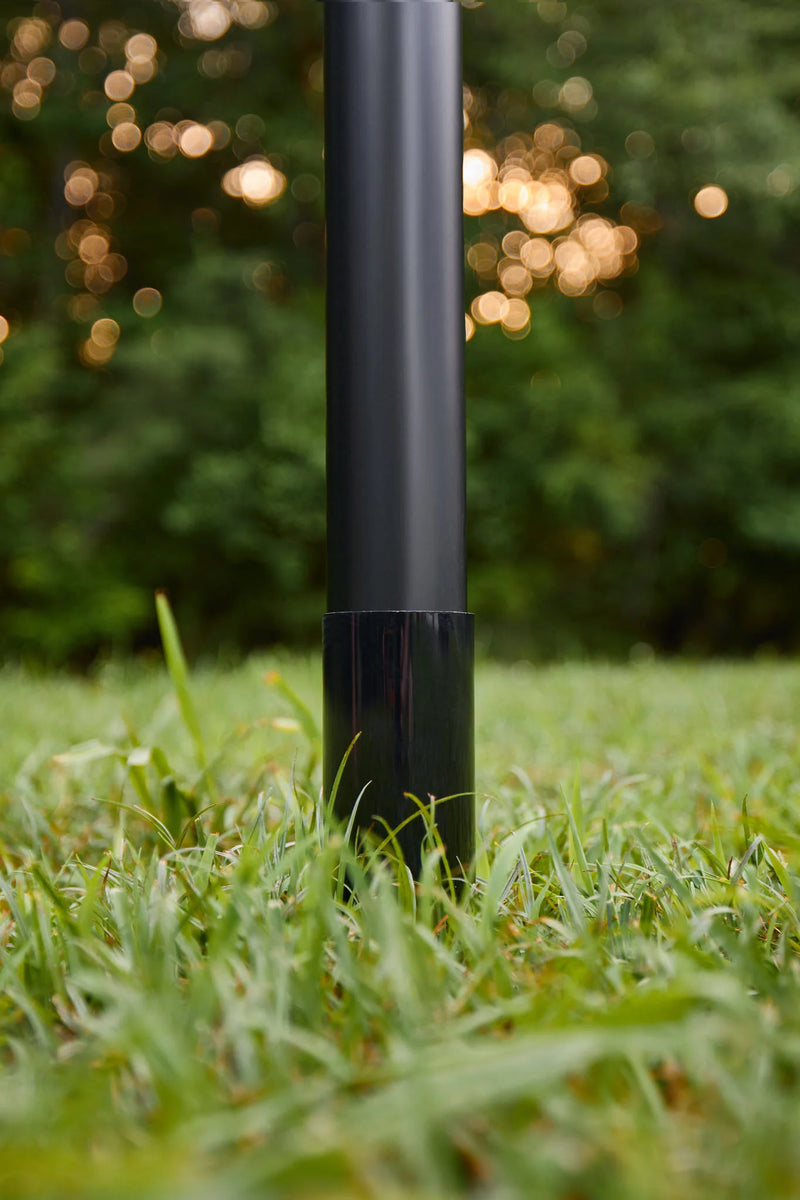 Load image into Gallery viewer, Bottom section of the black Fairybell Sectional Aluminum Pole installed in the green grass with a blurred nature background.
