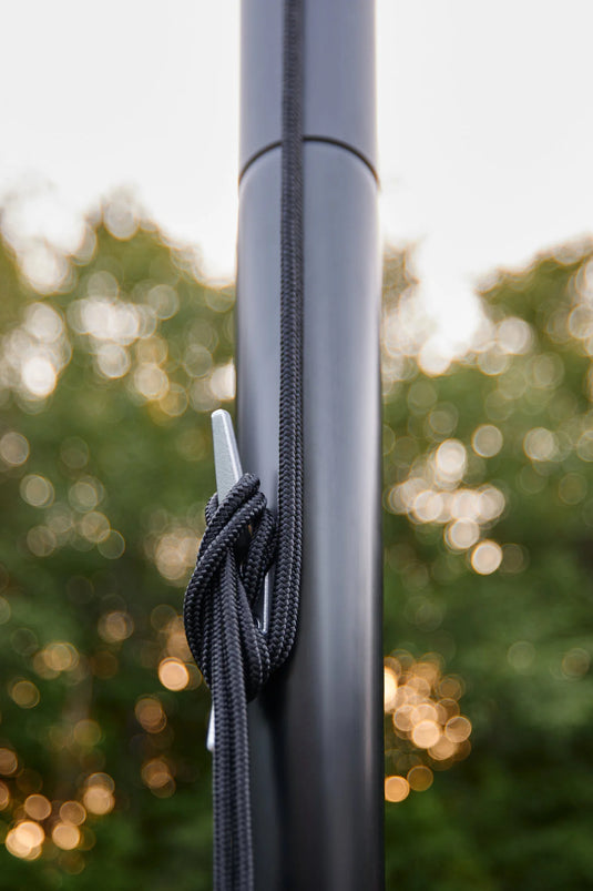 Close-up of the black rope halyard secured with a tight knot around the silver cleat on the black Fairybell Sectional Aluminum Pole.