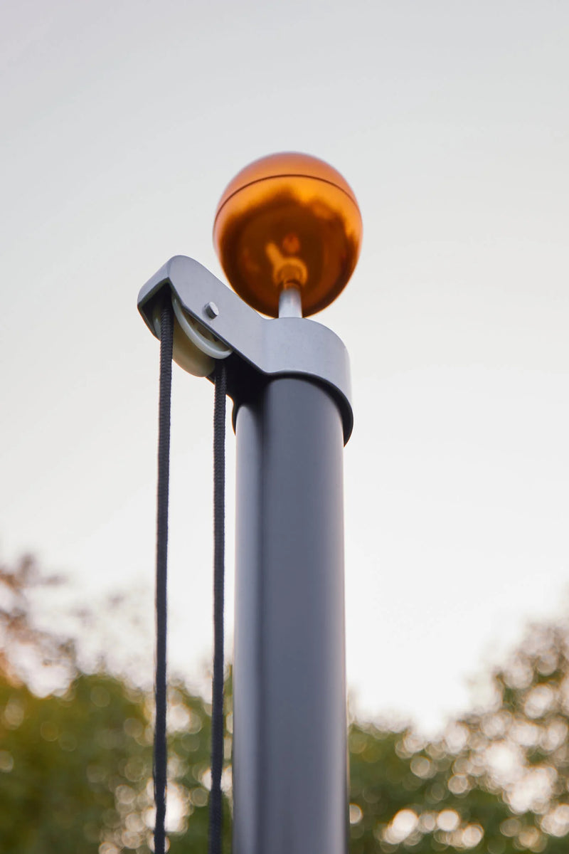 Load image into Gallery viewer, Close-up of the black Fairybell Sectional Aluminum Pole top, showing the pulley, halyard, and gold ball finial.
