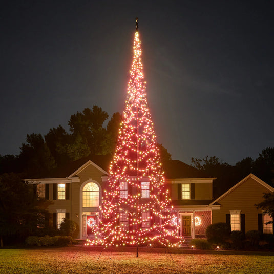 Tall outdoor Fairybell Single Color Flagpole Christmas Tree Light fully illuminated in festive red against a dark evening backdrop.