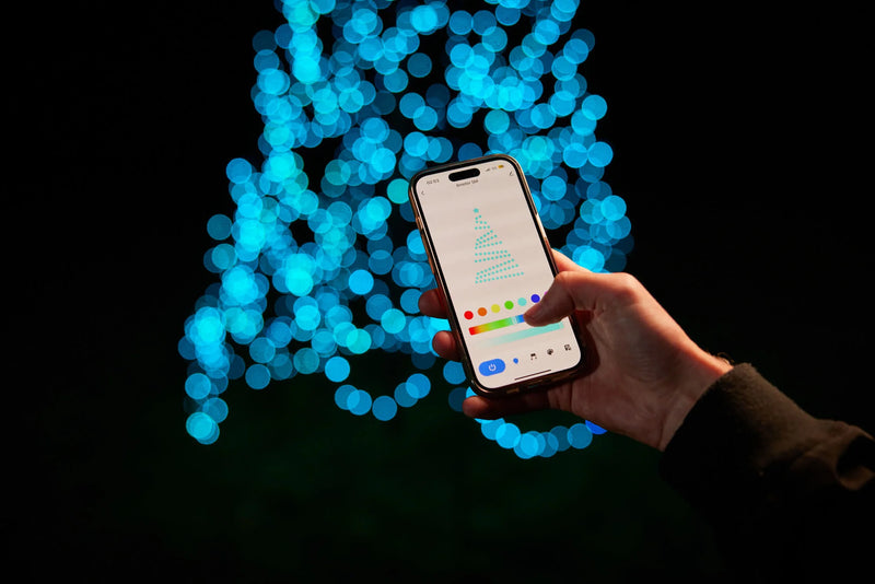 Load image into Gallery viewer, Hand using the color picker in the control app for the Fairybell Smart Magic Light against a background of blue bokeh lights.
