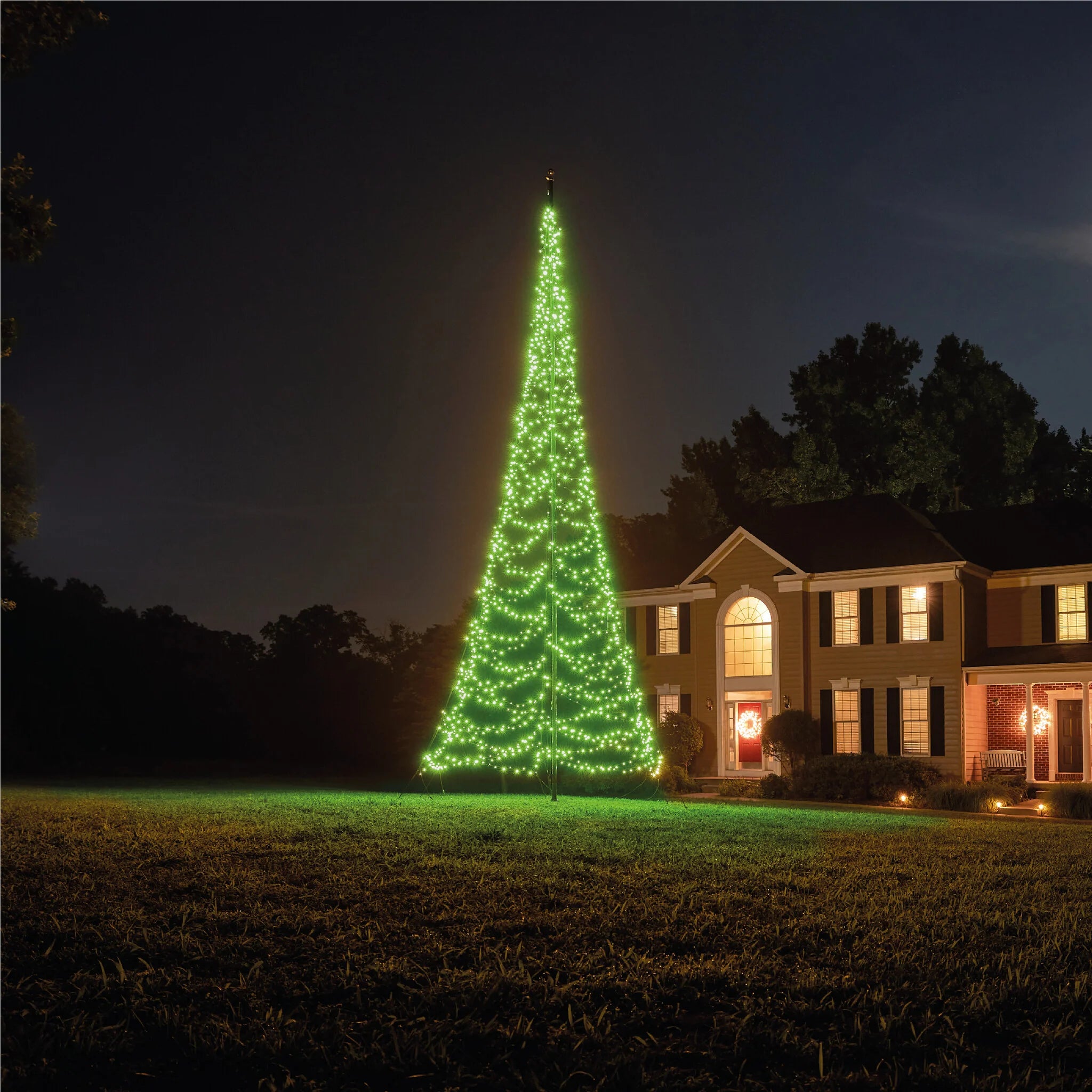 Fairybell Smart Magic Flagpole Christmas Tree Light illuminated in a pale mint green color in a residential yard.
