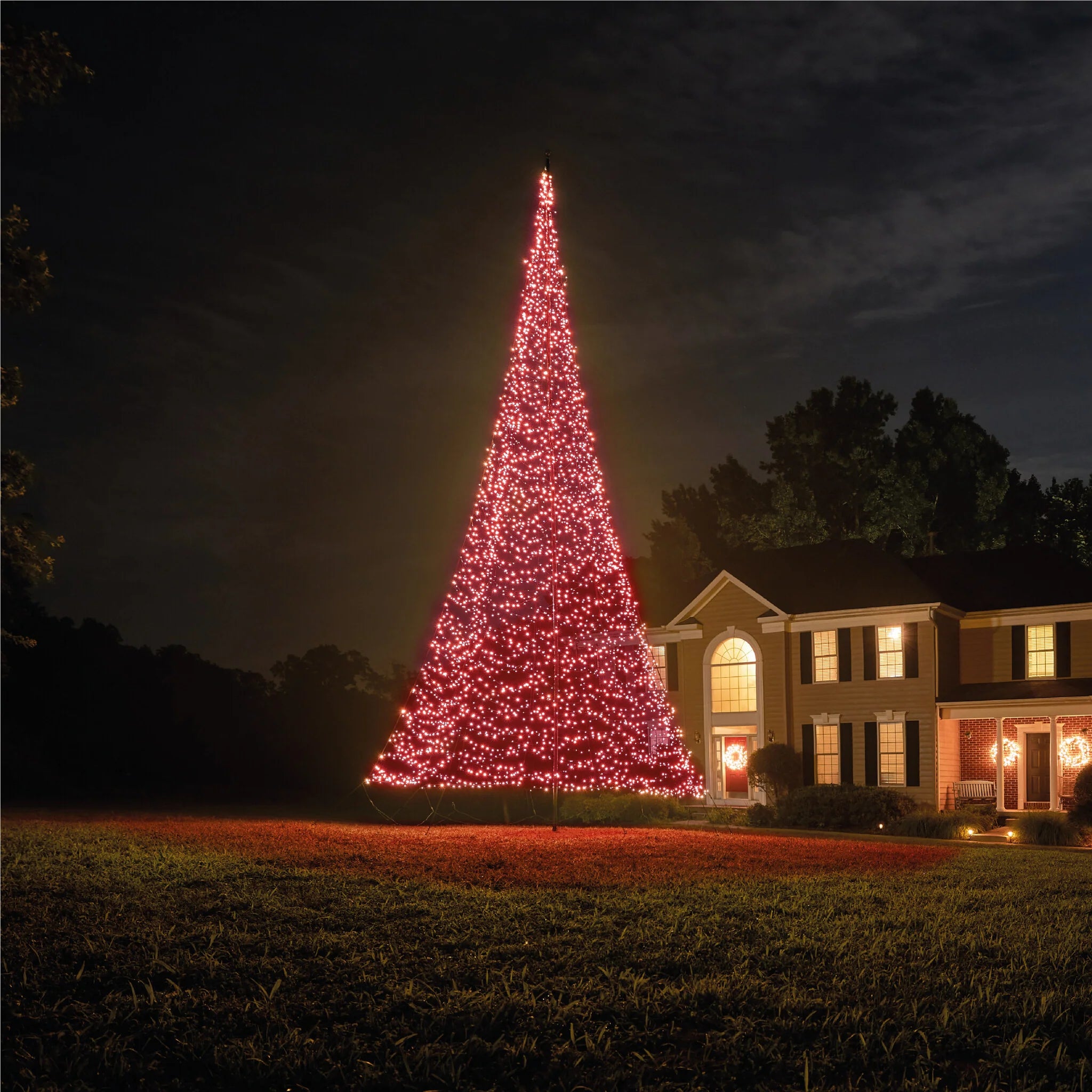 Fairybell Smart Magic Flagpole Christmas Tree Light illuminated in a deep red color, highlighting the residential holiday display.
