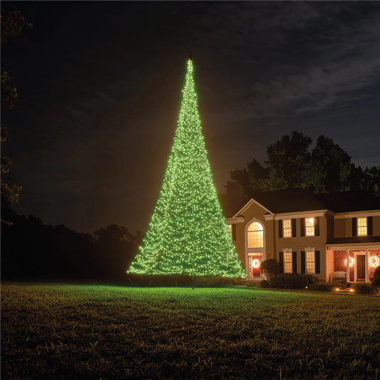 Fairybell Smart Magic Flagpole Christmas Tree Light illuminated in a warm yellowish-white color in a suburban front yard.
