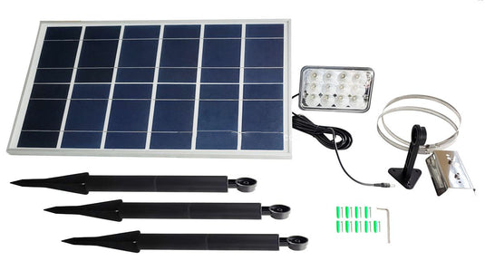 Full kit contents for the FPL Independence Solar Flagpole Light system. Components include the large solar panel, the rectangular LED light head, a connection cable, three black ground stakes for the light head, and mounting hardware/tools.