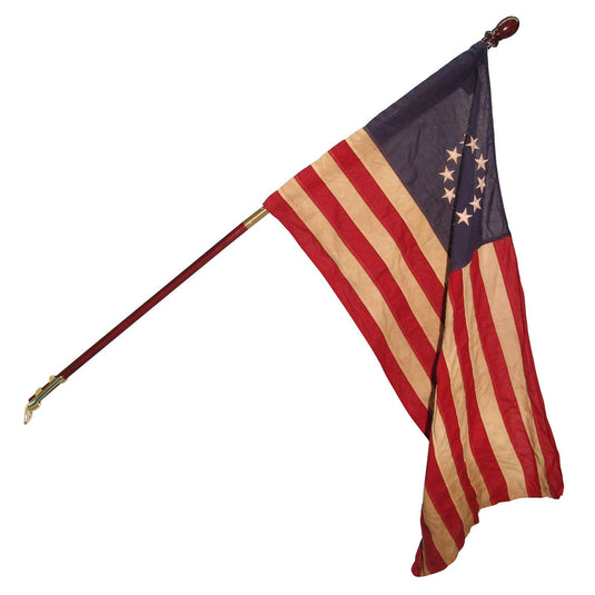 An antique-style U.S. 13-star flag attached to a slanted mahogany wood pole, often used for house mounting. The historical flag features a faded, tea-stained look with thirteen distressed stars arranged in a circle, signifying the Revolutionary War era.