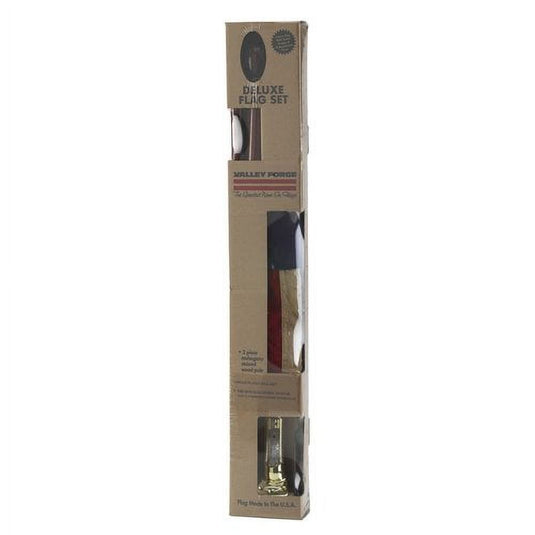 Retail packaging of the Heritage Series U.S. Flag Kit, showing the long cardboard box. Visible items inside the box window are the mahogany-finish wood pole, a partially folded flag, and the nickel-finish mounting bracket hardware at the bottom.