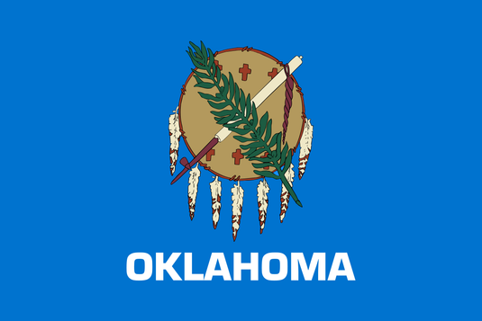 Oklahoma state flag featuring a sky-blue field with a traditional Osage Nation buffalo-skin shield adorned with eagle feathers, a peace pipe, and an olive branch crossed over it, symbolizing unity and peace.