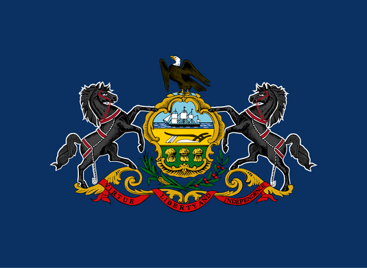Pennsylvania state flag with a blue background featuring the state coat of arms: a shield with a ship, plow, and wheat, flanked by black horses, topped with a bald eagle, and a red ribbon reading “Virtue, Liberty and Independence.”