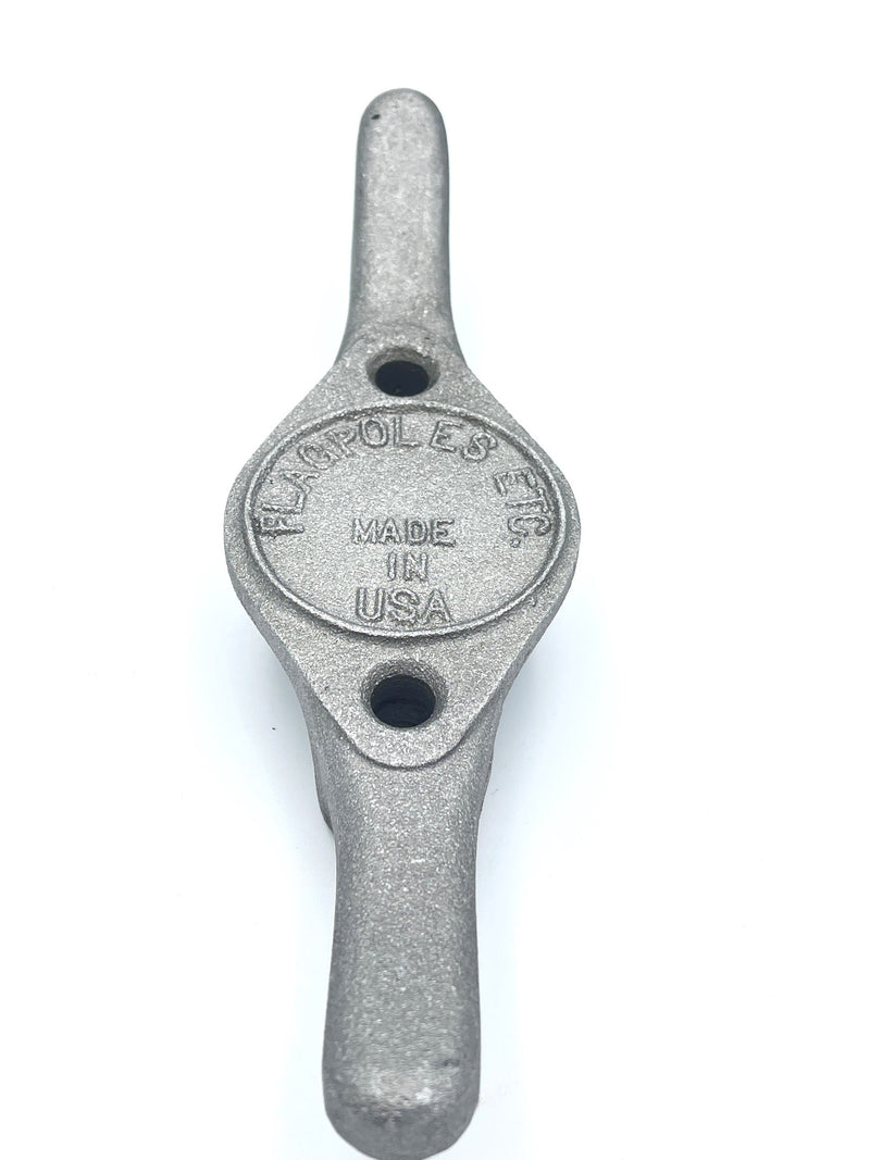 Load image into Gallery viewer, Heavy-duty, cast aluminum Flagpole Cleat with a textured silver finish. The cleat is centered by an oval plate stamped with "MADE IN USA" and includes two screw holes for mounting the halyard hardware.
