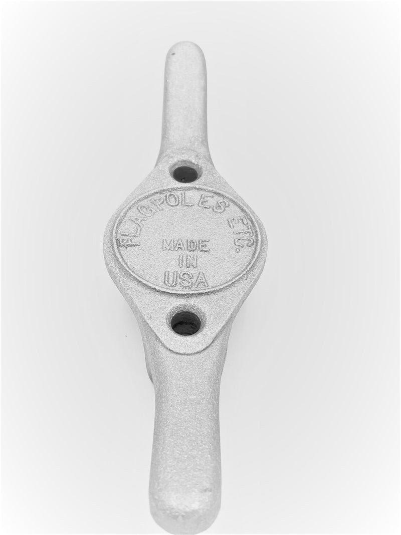 Load image into Gallery viewer, Top-down view of the Heavy Duty Cast Aluminum Flagpole Cleat in a light, slightly reflective white  color, emphasizing the detailed texture of the cast metal and the prominent "MADE IN USA" stamping on the center mounting pad.

